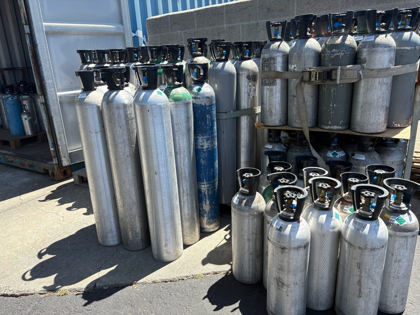 Rows of aluminum CO2 tanks in multiple sizes, filled and staged for refill and exchange