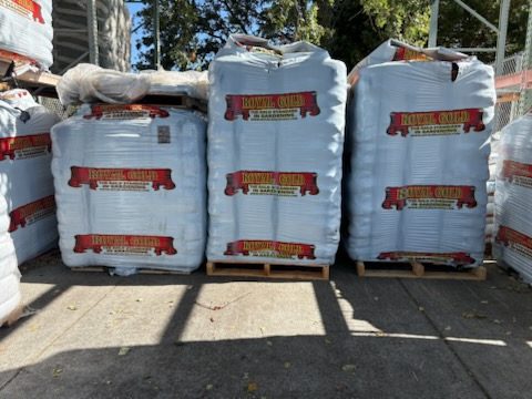Shrink-wrapped pallets of Royal Gold potting soil bags staged in the outdoor yard